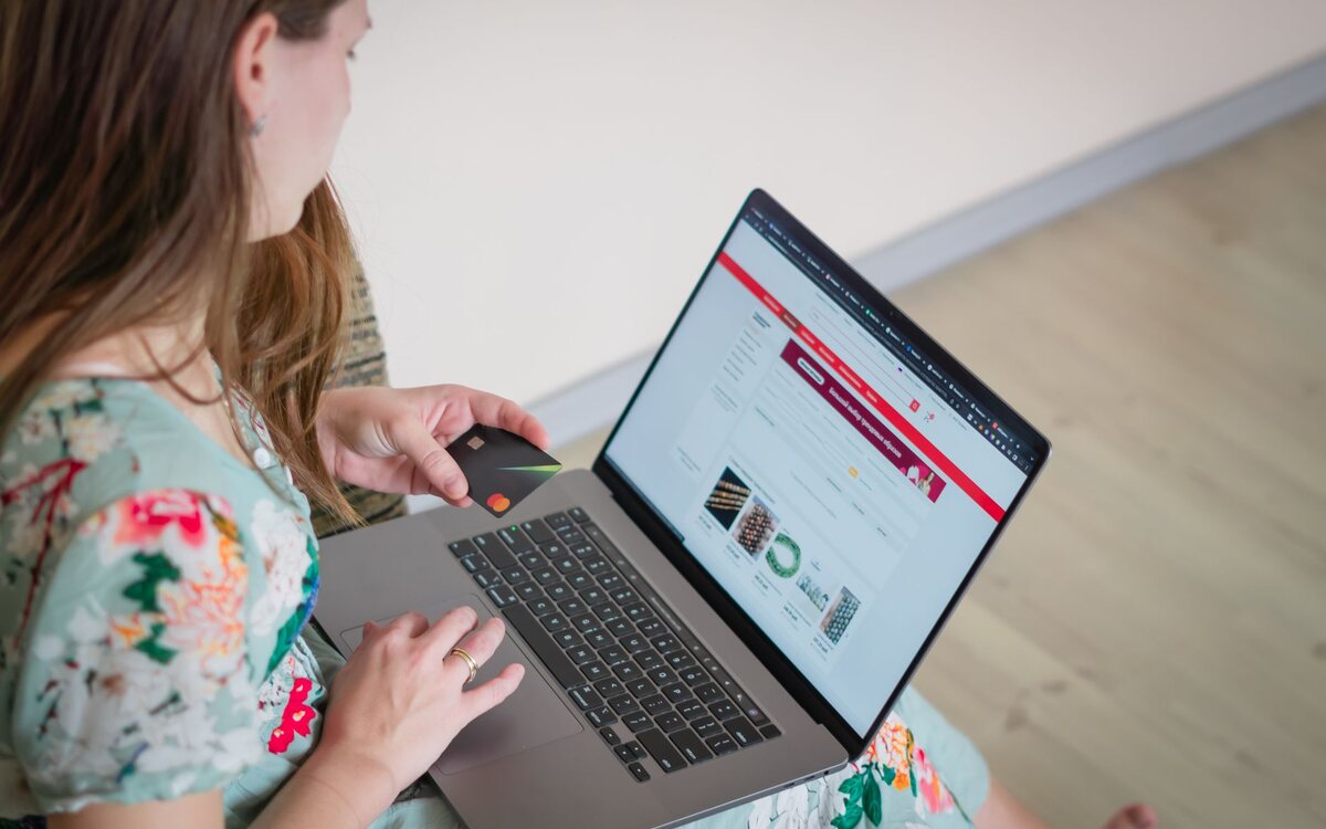Pessoa comprando pela internet no notebook com o cartão na mão