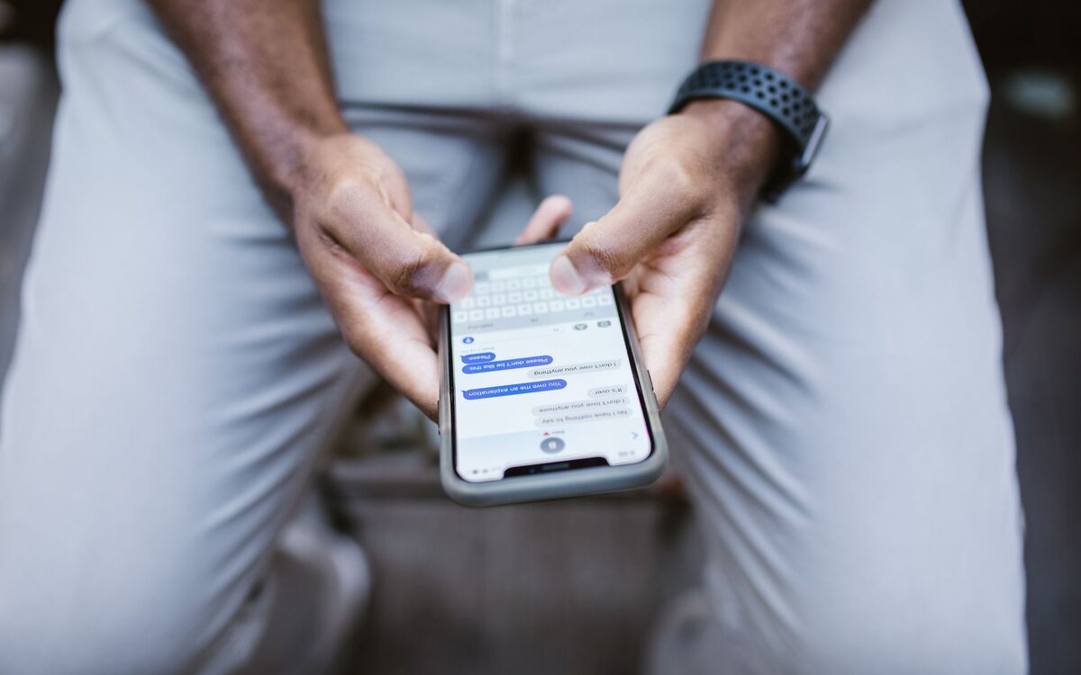 Mãos segurando um celular durante uma conversa por mensagem