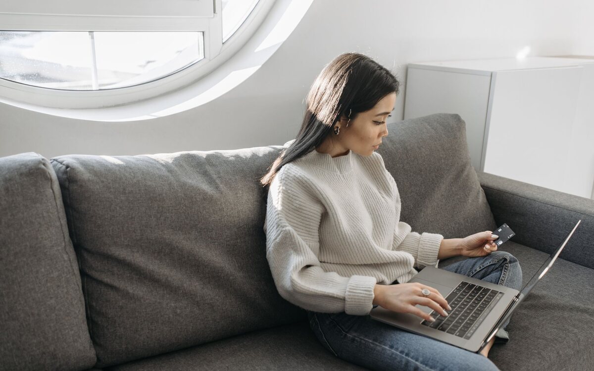 Mulher comprando pela internet no sofá de casa