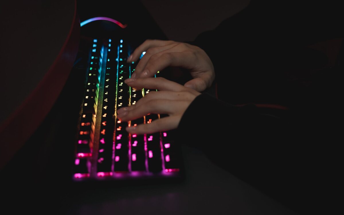 Mãos digitando em um teclado sobre uma mesa escura