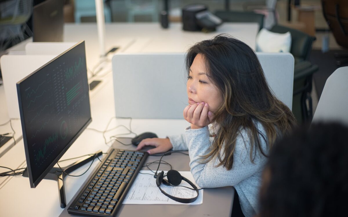 Mulher trabalhando diante de monitores em um escritório